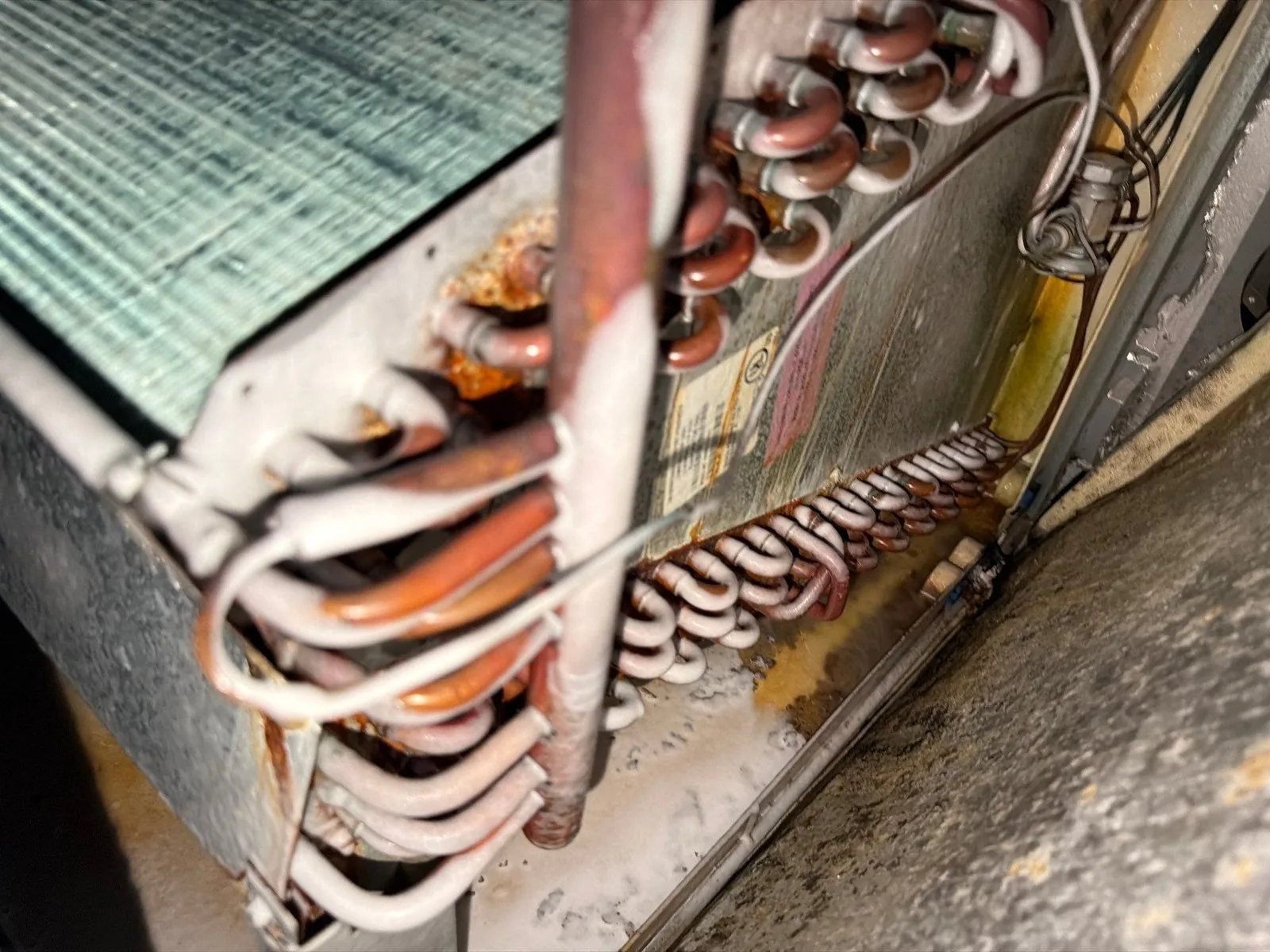 An older indoor coil with corrosion on the copper and in the drain pan